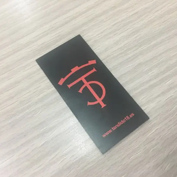 Etiqueta de cartón negra con letras y logo en color rojo